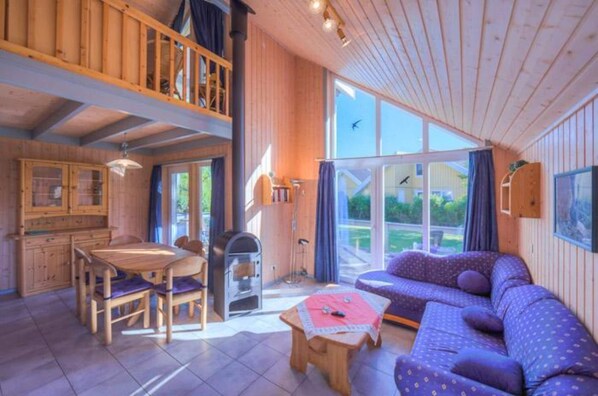 A cozy cabin interior with a dining area, a sofa, and a fireplace.