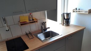 Una cocina moderna con un lavamanos, una cafetera y un organizador para especias.