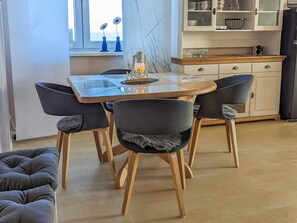 A dining area with a wooden table and four chairs, a kitchen with cabinets and a countertop, and a window with a view.