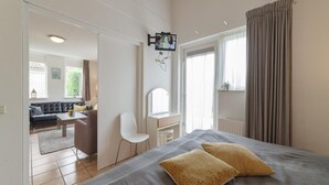 A bedroom with a bed, two pillows, a desk, a chair, and a television mounted on the wall. - Holiday Home in Zeeland With Garden (Wemeldinge)