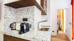 A compact kitchen with a speckled backsplash, a coffee maker, a toaster, and a sink.