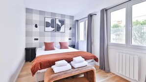 Een moderne slaapkamer met een groot bed, een bankje, uitzicht op de omgeving en kunst aan de muur.