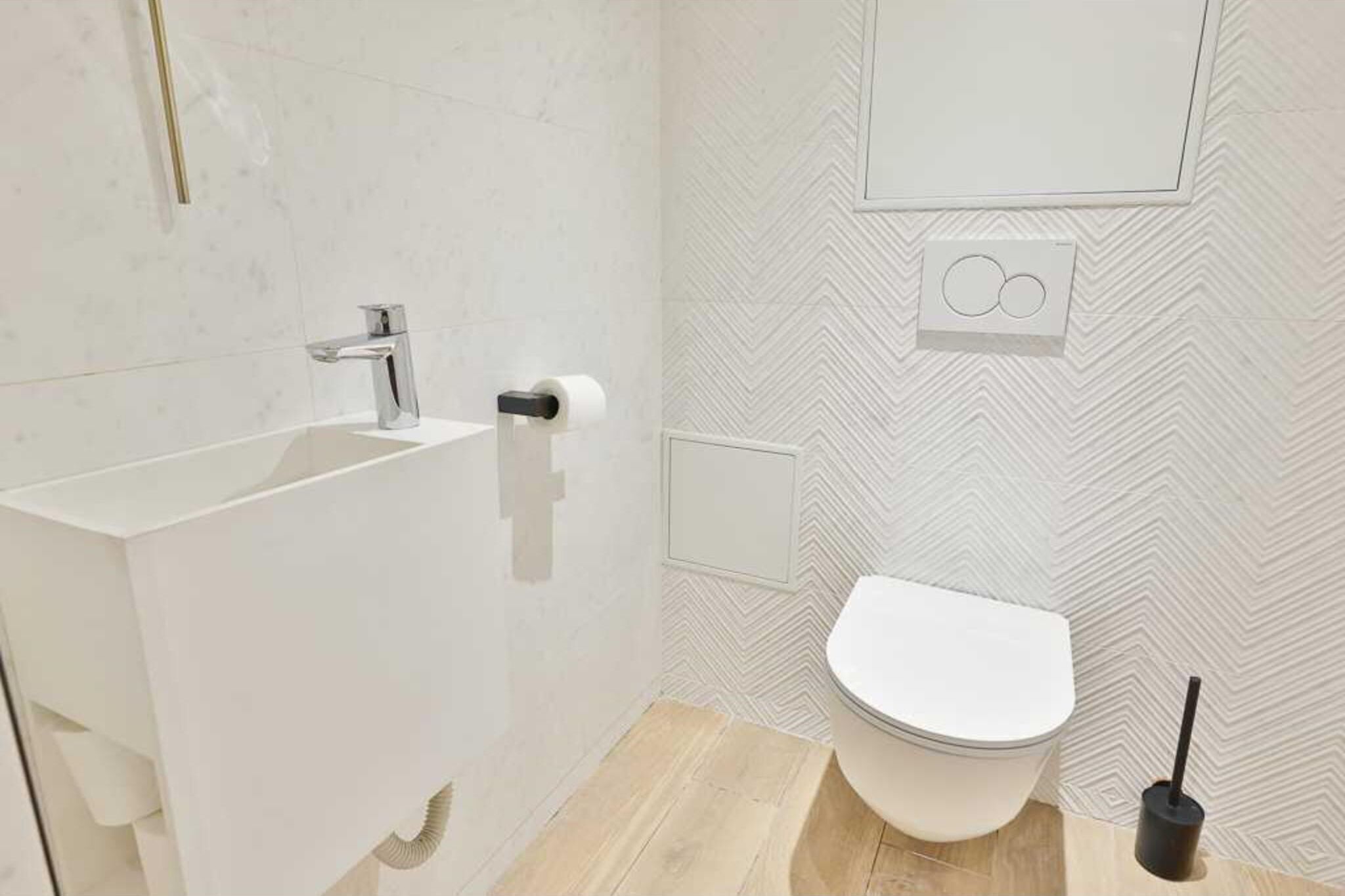 Une salle de bain moderne avec un lavabo, des toilettes et une douche, le tout de couleur blanche.