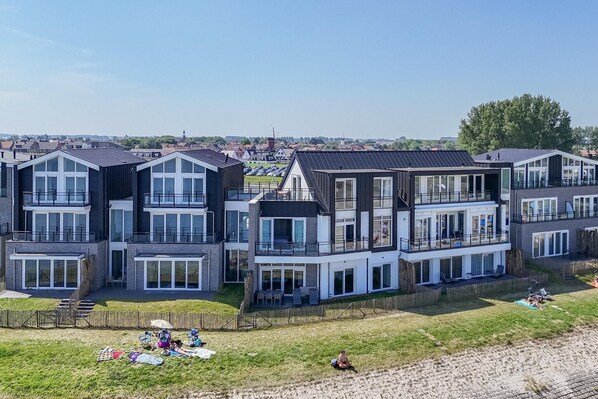 Un moderno edificio residencial con varios balcones y ventanas amplias.