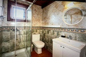 A bathroom with a glass shower enclosure, a toilet, and a sink with a mirror above it. - Beautiful Villa in Playa Blanca (Lanzarote)
