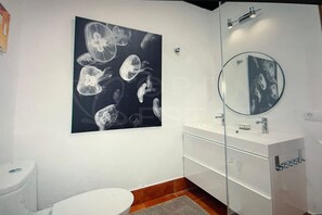 A bathroom with a white sink, a mirror, and a wall-mounted artwork of jellyfish. - Beautiful Villa in Playa Blanca (Lanzarote)