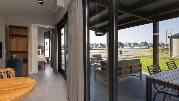 Quarto de hotel moderno com uma grande porta de vidro deslizante que dá para um espaço de pátio externo.