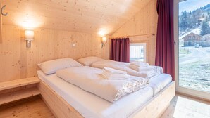 A wooden cabin room with a bed, two wall-mounted lights, and a window with curtains. - Appealing Chalet With hot tub (Sankt Georgen am Kreischberg)
