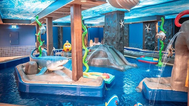 Un parco acquatico al coperto con scivoli, giochi gonfiabili e un’onda artificiale.