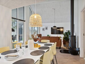 A modern dining area with a large table, yellow chairs, and a unique pendant light. - 5 Star Holiday Home in Otterup (Otterup)