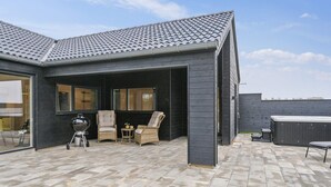 Une terrasse extérieure moderne, dotée d’un toit en tuiles, d’un barbecue, de meubles en osier et d’un jacuzzi.