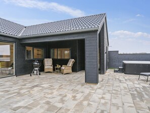 A modern outdoor patio with a tiled roof, a barbecue grill, wicker furniture, and a hot tub. - 5 Star Holiday Home in Otterup (Otterup)