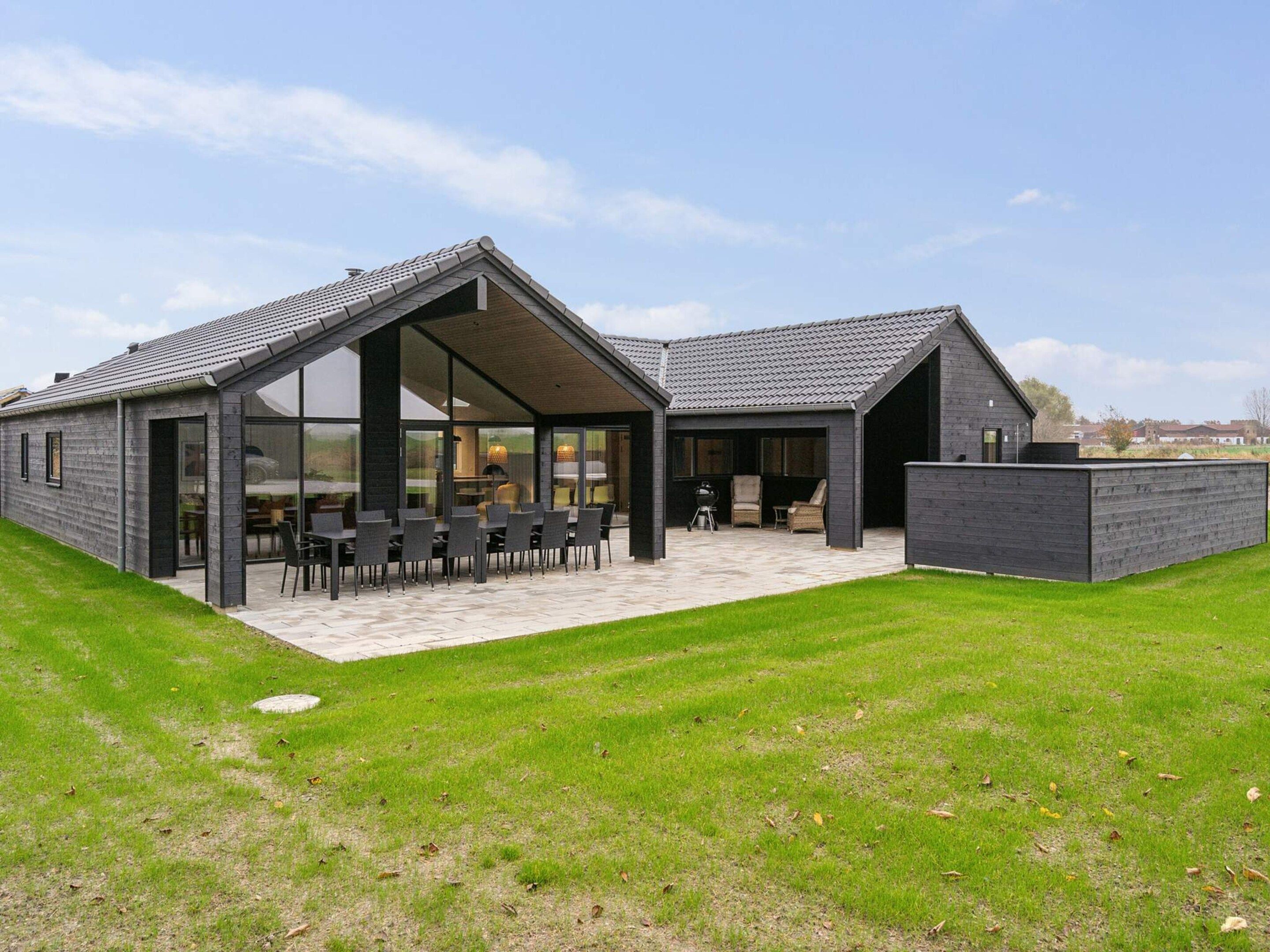 A modern house with a patio area, large windows, and a covered outdoor seating space.