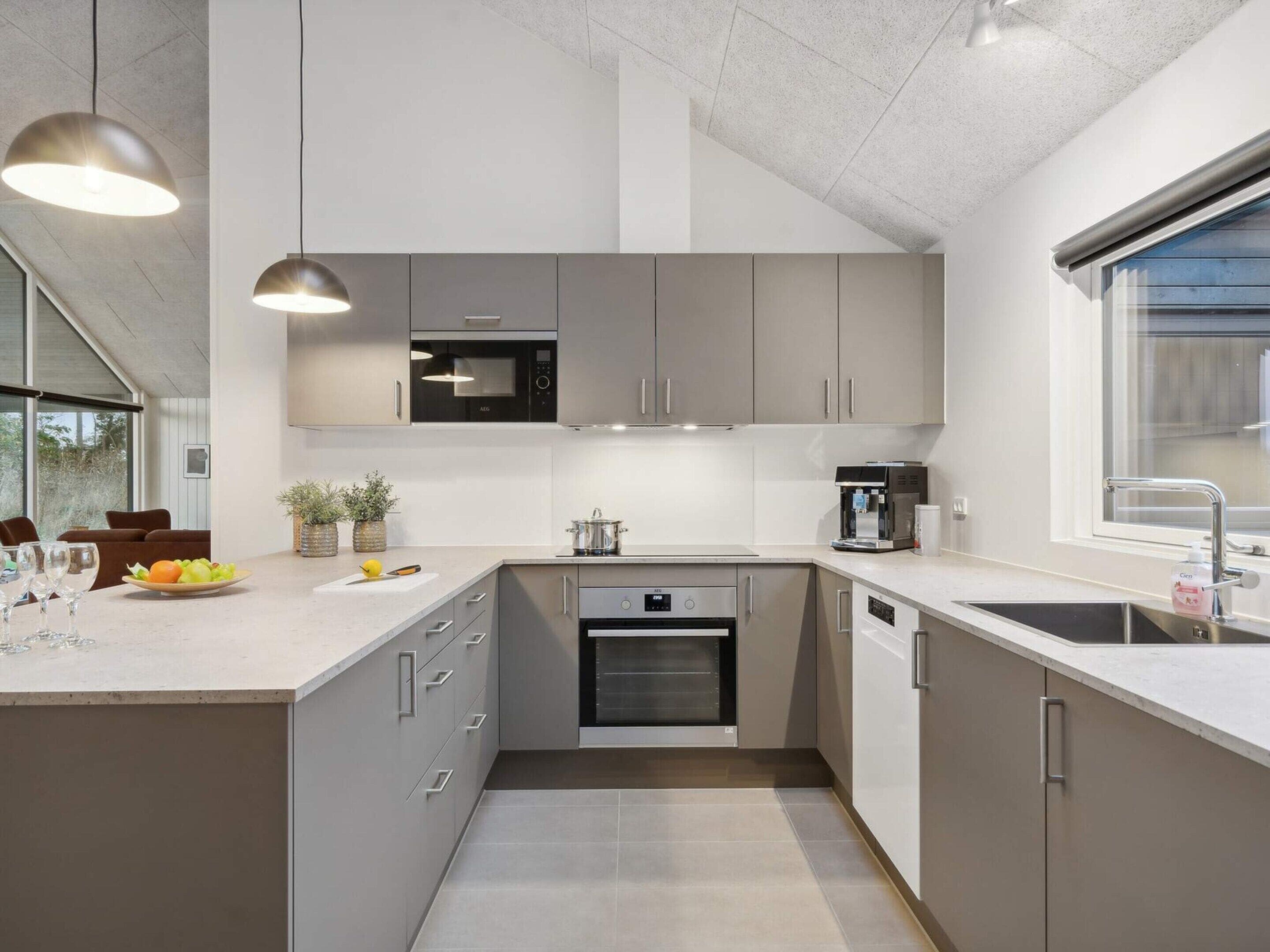 Una cocina moderna con armarios grises, horno integrado, cafetera y lavabo.
