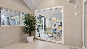 Une salle de bain moderne avec un grand miroir, une plante en pot et un espace douche.