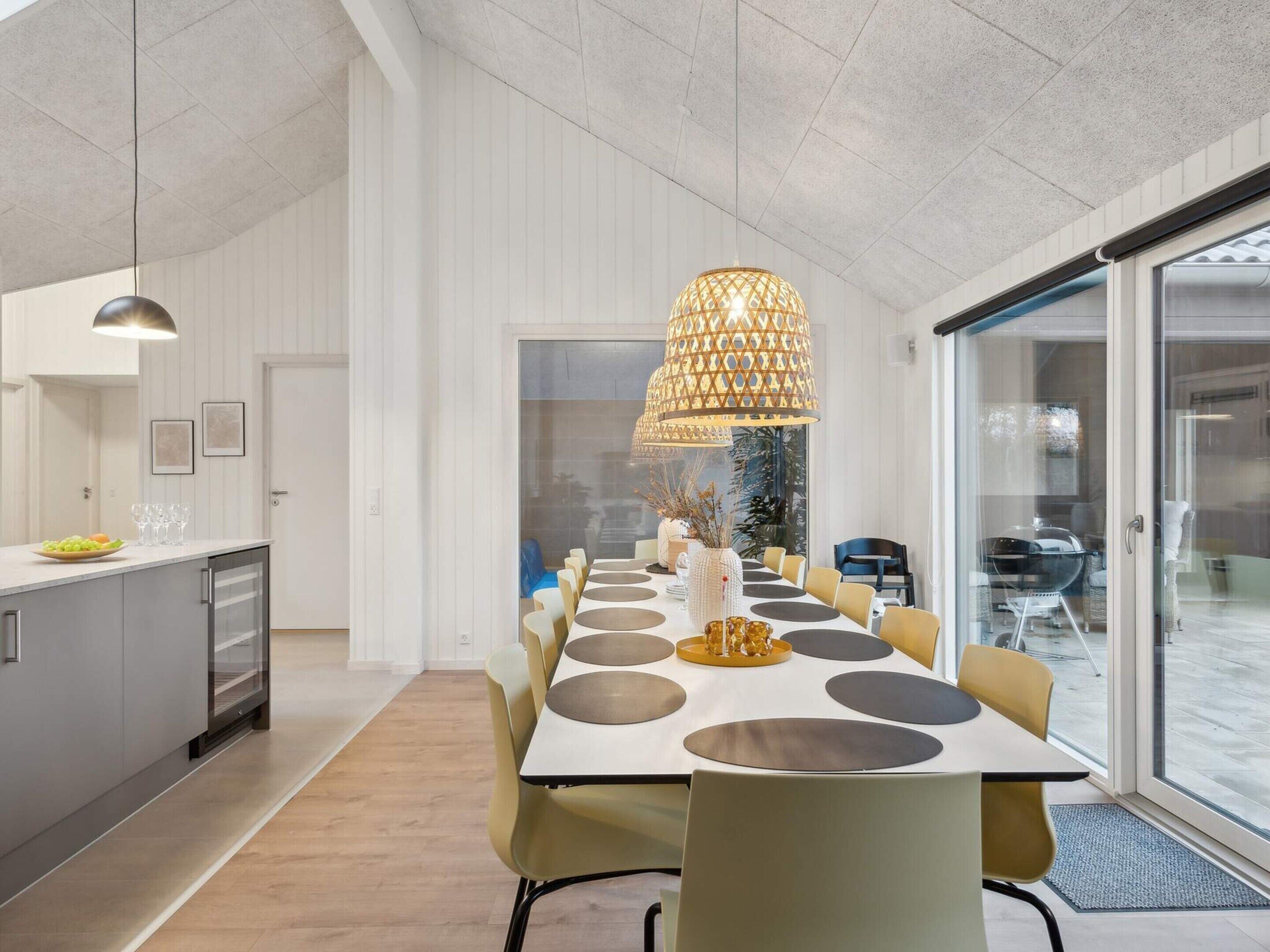 Un comedor moderno con una mesa larga, sillas e iluminación colgante.