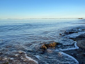 A calm body of water with waves gently lapping onto a rocky shore. - 5 Star Holiday Home in Otterup (Otterup)