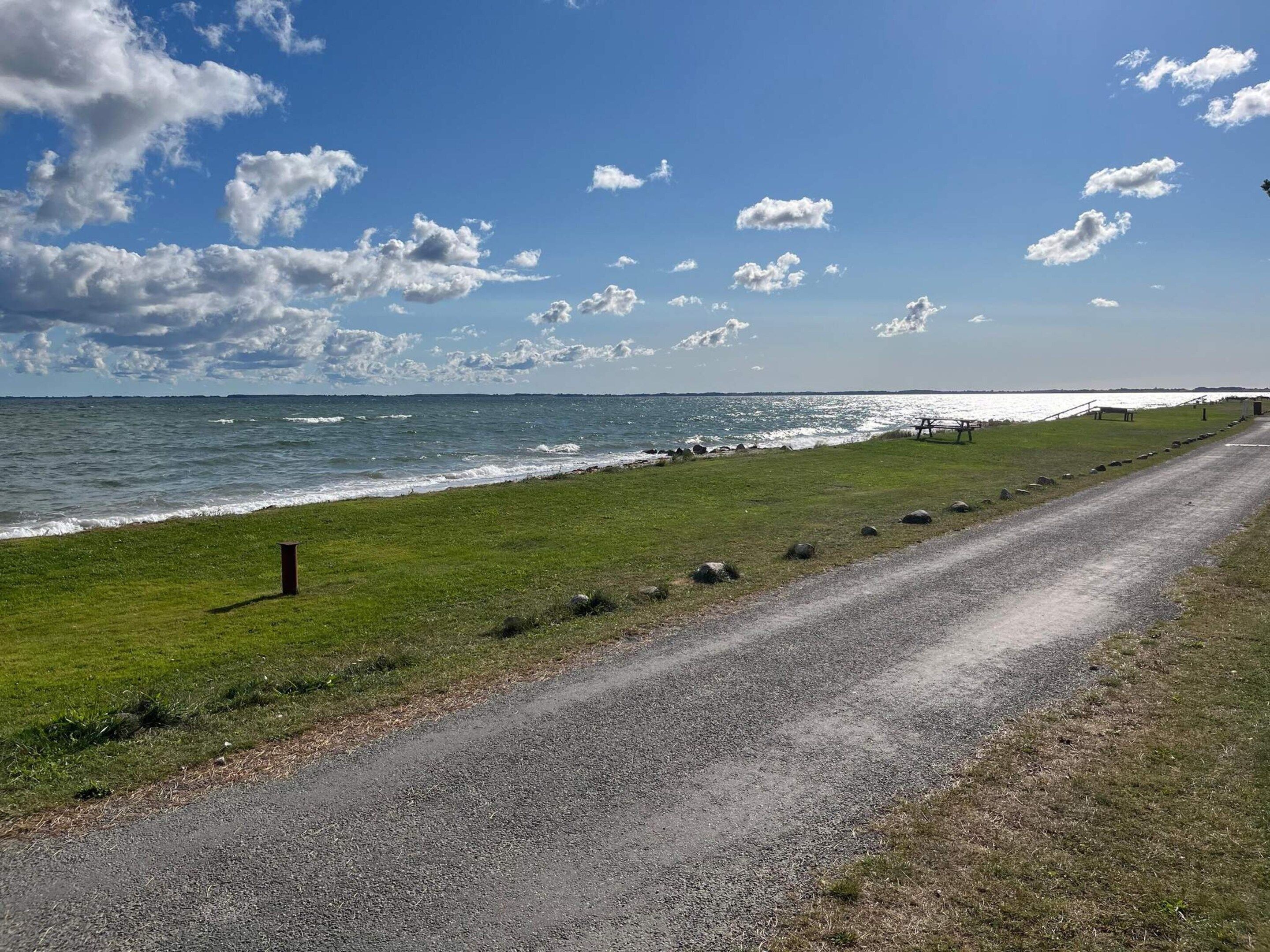 Une route côtière bordée d’une zone herbeuse et offrant une vue sur la mer.