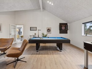 A modern indoor pool table with a dartboard and a billiards cue rack. - 5 Star Holiday Home in Otterup (Otterup)