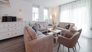 A modern living room with a sofa set, a coffee table, and a white cabinet. - Holiday Home in Zeeland With Garden Terrace (Wemeldinge)