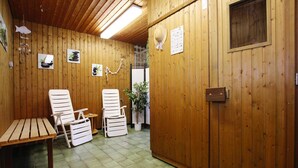 A wooden room with two white chairs, a small table, and a potted plant.