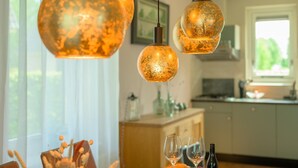 A dining area with a round table, two wine glasses, a bottle of wine, and a loaf of bread. - Bungalow in Sondel Near Slotermeer Lake (Sondel)