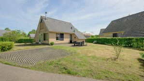 A residential property with a paved driveway, a grassy lawn, and a small patio area with outdoor furniture. - Bungalow in Sondel Near Slotermeer Lake (Sondel)