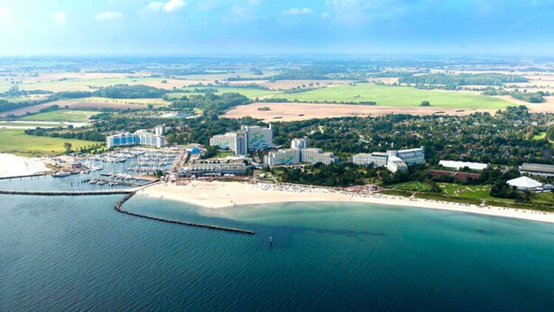 An aerial view of a coastal resort with multiple buildings, a marina, and a beach. - Ferienhaus im Ostseebad Damp (Damp)