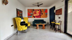 A modern living room with a yellow armchair, a teal sofa, and a coffee table. - Fun O Peace (Noida)