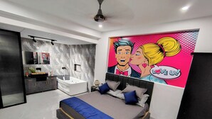 A modern bedroom with a large bed, a built-in vanity, and a pop art mural. - Fun O Peace (Noida)
