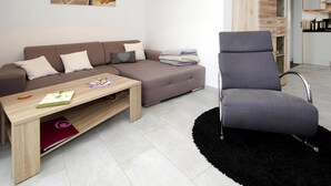 A modern living room with a sofa, a chair, a coffee table, and a black rug. - Ferienhaus Albatros in Nessmersiel (Dornum)
