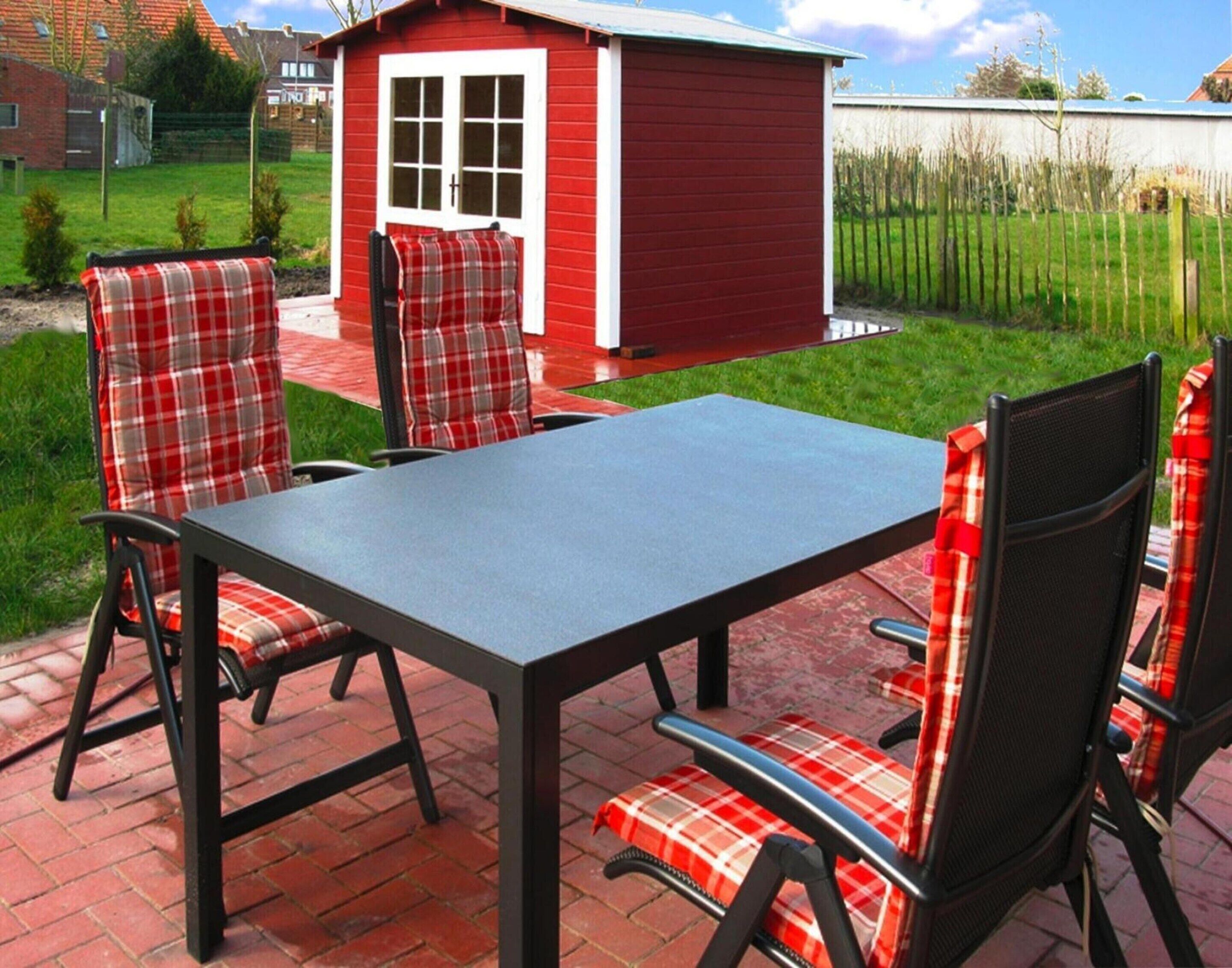 Een terras met een tafel en vier stoelen, elk met geruit kussens.