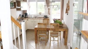A kitchen with a dining table and chairs, a stove, and a sink. - Exklusives Appartement in Rechlin (Rechlin)