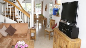 A living room with a sofa, coffee table, TV, wooden cabinet, and a staircase. - Exklusives Appartement in Rechlin (Rechlin)