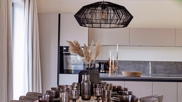 A modern kitchen with a dining table set for four, featuring a variety of glassware and a decorative vase with dried plants. - Houseboat With Private Roofed Terrace (Zeewolde)