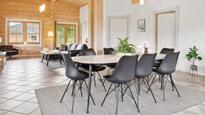 A dining area with a wooden ceiling, a round table, and black chairs.