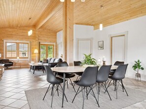 A dining area with a wooden ceiling, a round table, and black chairs.