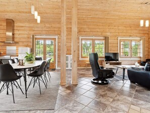 Ein modernes Blockhaus-Interieur mit Essbereich, Sitzgelegenheiten und Fernseher.