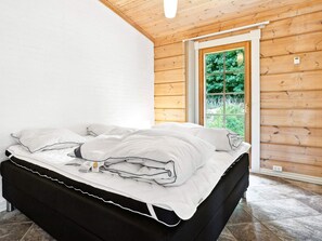 Quarto com cama, janela e teto de madeira.