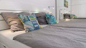 Une chambre à coucher moderne avec un lit, une literie grise et des coussins décoratifs.