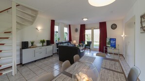 A modern living room with a sofa, dining table, and staircase. - Spacious Holiday Home With Sauna Near Beach (Wemeldinge)