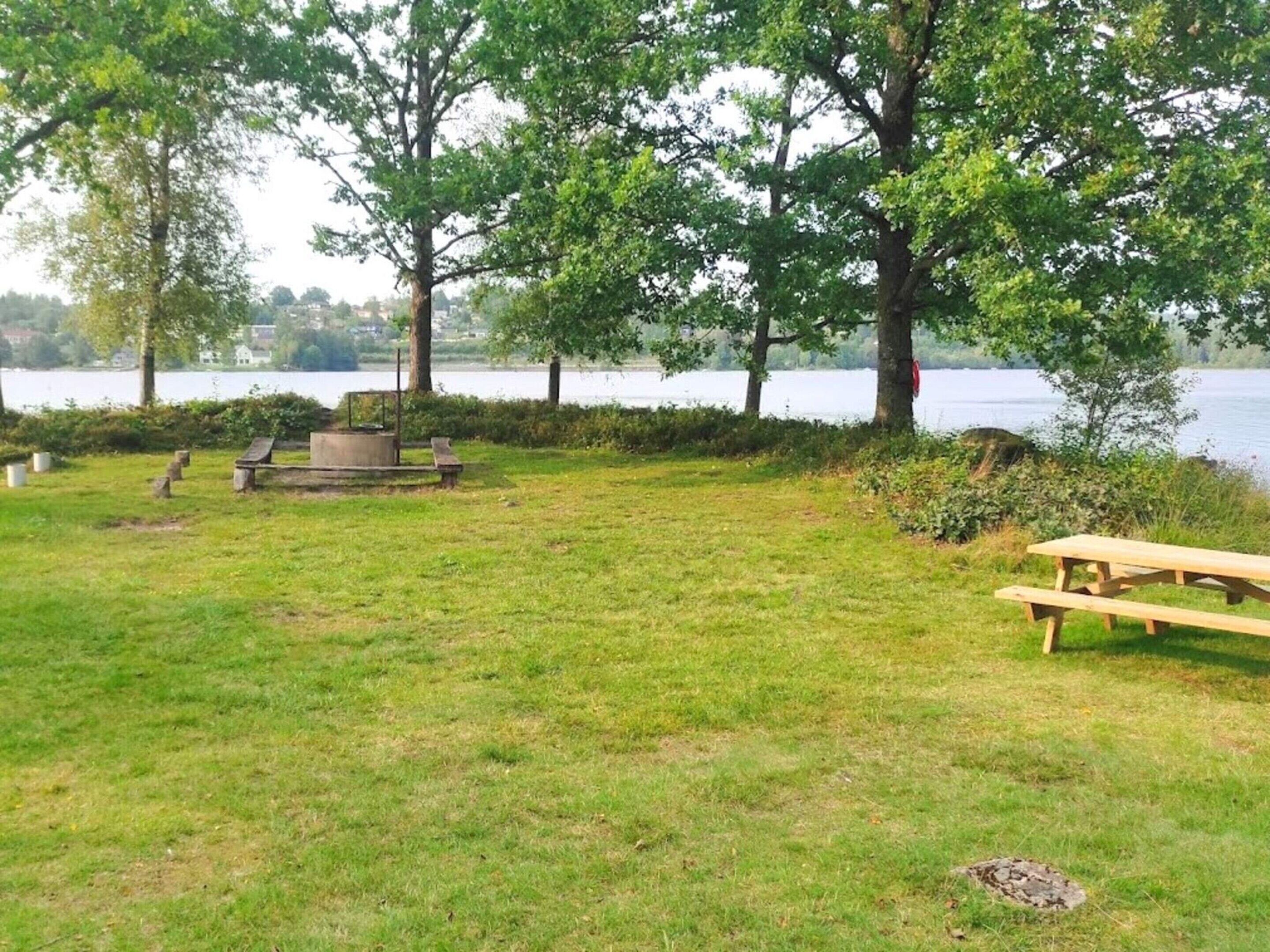 Un parque con césped, mesas de picnic y una fogata.