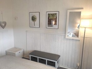 A bedroom with a bed, a bench, a bedside table, a lamp, and two framed pictures on the wall. - 4 Star Holiday Home in Boras (Borås)