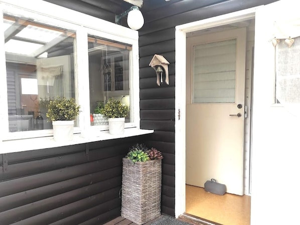 A dark wooden exterior with a white-framed window, a door, and a small bell on the wall. - 4 Star Holiday Home in Boras (Borås)