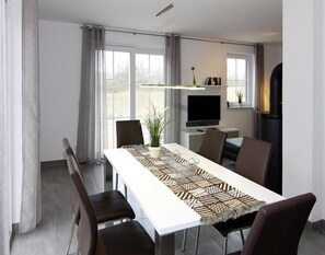 Enjoy meals in this stylish dining area with a long table, dark chairs, and a decorative runner.