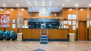 A reception area with a wooden counter, a map, and a statue. There are blue strollers and a trash bin.