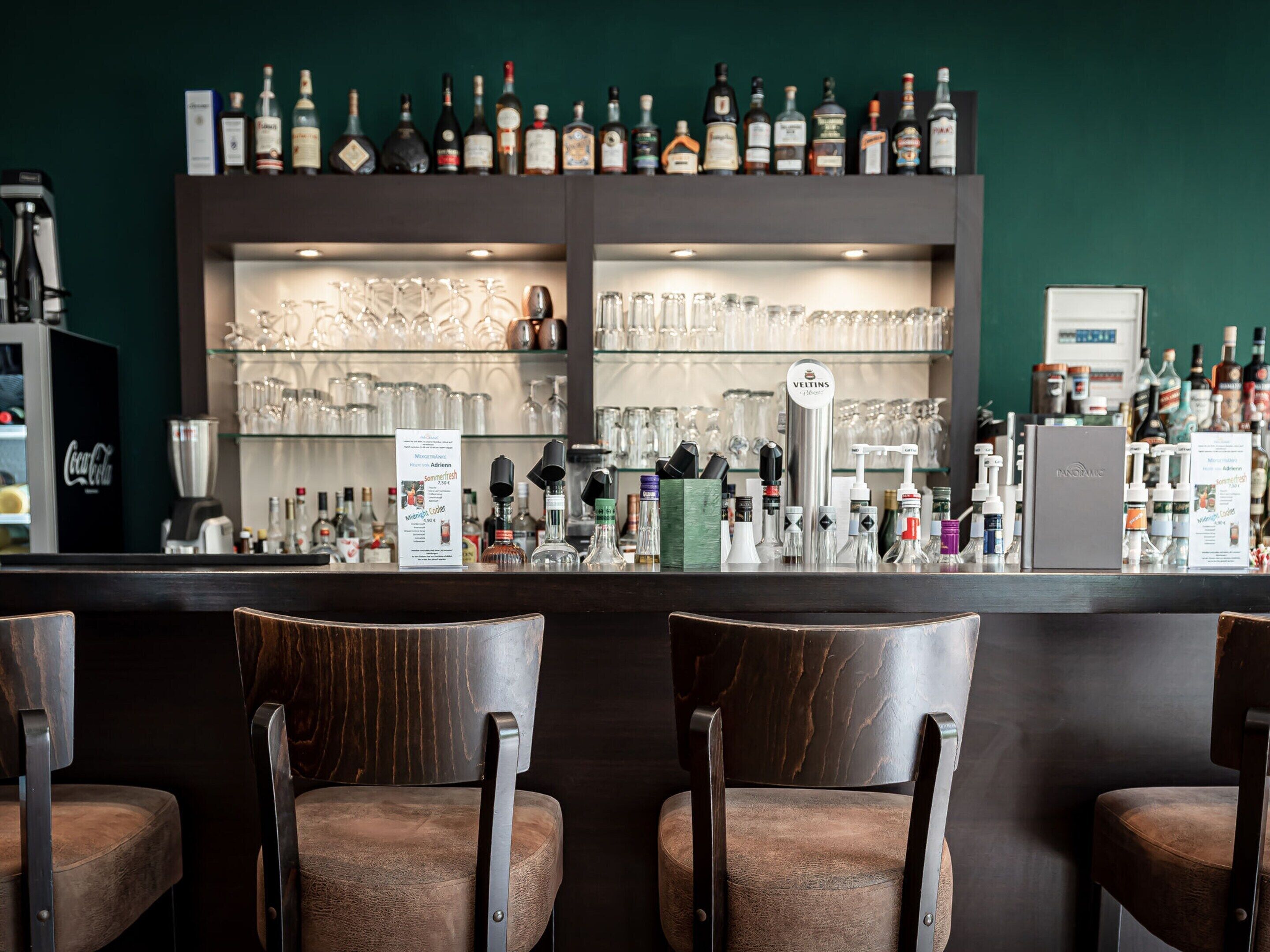 A bar area with multiple liquor bottles, glasses, and a menu sign.