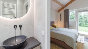 A modern bathroom with a large oval sink, a mirror, and a toilet. The bathroom has a clean, minimalist design with white tiles and a wooden ceiling. - Holiday Home in Quiet Park With Garden (Wemeldinge)