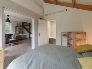 Une chambre à coucher avec un lit, une armoire en bois et un escalier menant à une autre pièce.