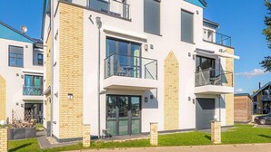 A modern two-story residential building with large windows, a balcony, and a garage. - Liebevoll Eingerichtetes Appartement (Rechlin)